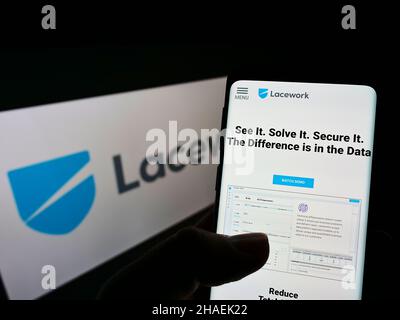 Personne tenant un smartphone avec une page Web de la société américaine de sécurité du cloud, Lacwork Inc., affichée à l'écran devant le logo.Concentrez-vous sur le centre de l'écran du téléphone. Banque D'Images