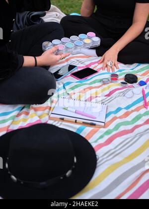 deux jeunes femmes assises avec les jambes croisées, l'une d'entre elles ramassant les peintures Banque D'Images