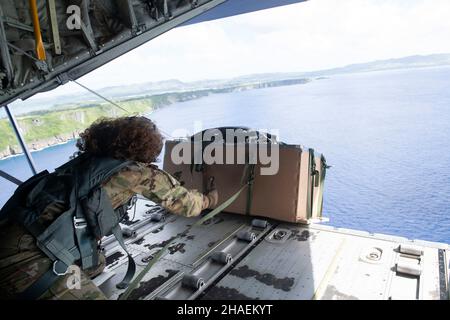 Orote Island, États-Unis.03 décembre 2021.Kim Doyle, chef de l'aviation américaine, charge du 36th escadron de transport aérien, pousse un paquet de cargaison de la baie de chargement d'un avion C130 pendant l'opération annuelle chute de Noël 70th le 3 décembre 2021 au-dessus de l'île d'Orote, à Guam.Chaque année en décembre, les équipages ont fait don de nourriture, de fournitures, de matériel éducatif et d'outils à 55 nations insulaires du Pacifique Sud-est.Crédit : TSgt.Joshua Edwards/US Airforce photo/Alamy Live News Banque D'Images