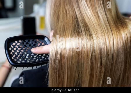 Gros plan homme professionnel coiffeur styliste main tenir femme longue lisse brillant teint verrou de cheveux doré.Femme client retour nouveau Banque D'Images
