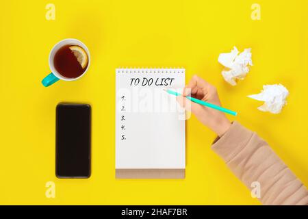 Concept de liste des tâches.Couleur menthe tasse à thé et carnet avec liste à faire sur le bureau jaune clair d'en haut, planification et concept de conception.Vue de dessus, plan d'appartement Banque D'Images