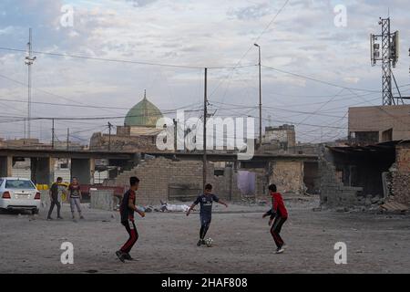 Mossoul, Irak.25th novembre 2021.Les enfants ont vu jouer au football dans une cour près de voitures brûlées à Mossoul.(Photo par Ismael Adnan/SOPA Images/Sipa USA) crédit: SIPA USA/Alay Live News Banque D'Images