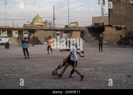 Mossoul, Irak.25th novembre 2021.Les enfants ont vu jouer au football dans une cour près de voitures brûlées à Mossoul.(Photo par Ismael Adnan/SOPA Images/Sipa USA) crédit: SIPA USA/Alay Live News Banque D'Images