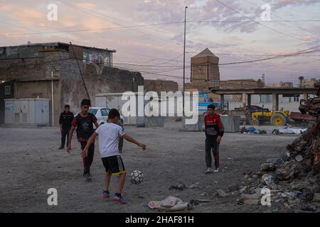 Mossoul, Irak.25th novembre 2021.Les enfants ont vu jouer au football dans une cour près de voitures brûlées à Mossoul.(Photo par Ismael Adnan/SOPA Images/Sipa USA) crédit: SIPA USA/Alay Live News Banque D'Images