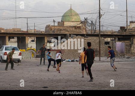 Mossoul, Irak.25th novembre 2021.Les enfants ont vu jouer au football dans une cour près de voitures brûlées à Mossoul.(Credit image: © Ismael Adnan/SOPA Images via ZUMA Press Wire) Banque D'Images