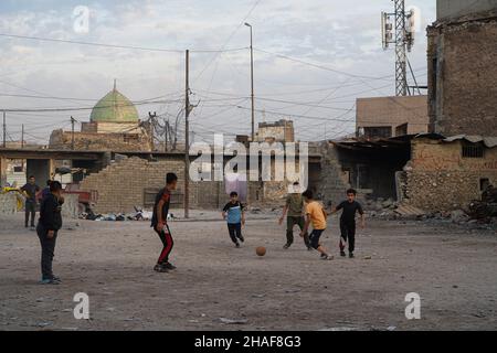 Mossoul, Irak.25th novembre 2021.Les enfants ont vu jouer au football dans une cour près de voitures brûlées à Mossoul.(Credit image: © Ismael Adnan/SOPA Images via ZUMA Press Wire) Banque D'Images