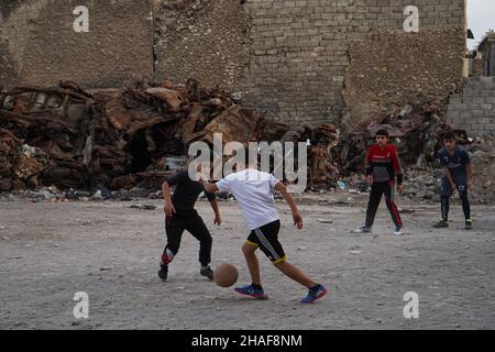 Mossoul, Irak.25th novembre 2021.Les enfants ont vu jouer au football dans une cour près de voitures brûlées à Mossoul.(Credit image: © Ismael Adnan/SOPA Images via ZUMA Press Wire) Banque D'Images