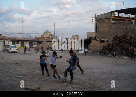 Mossoul, Irak.25th novembre 2021.Les enfants ont vu jouer au football dans une cour près de voitures brûlées à Mossoul.(Credit image: © Ismael Adnan/SOPA Images via ZUMA Press Wire) Banque D'Images