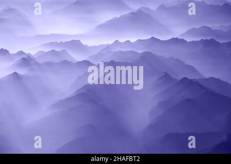 Nuages moelleux au-dessus des montagnes Alp, une vue de la fenêtre d'avion.Couleur de l'année 2022 très pery ton.Mise au point douce. Banque D'Images