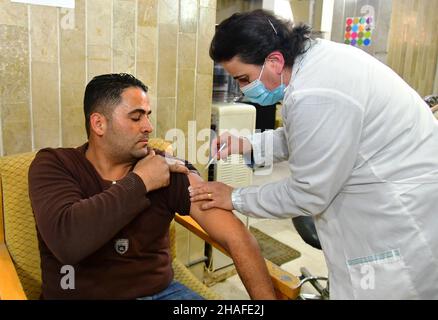 Damas.12th décembre 2021.Un homme reçoit une dose du vaccin COVID-19 à Damas, en Syrie, le 12 décembre 2021, dans le cadre d'une campagne visant à envoyer des équipes médicales mobiles pour vacciner les personnes contre le COVID-19 dans plusieurs régions et institutions.Crédit: Ammar Safarjalani/Xinhua/Alamy Live News Banque D'Images