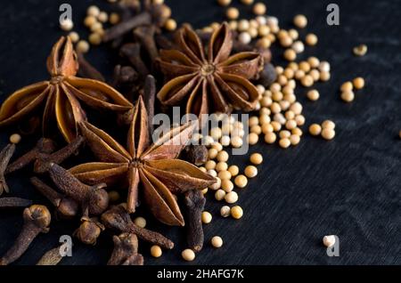 Macro image de Crove, d'anis étoilé et de graines de moutarde sur fond noir horizontal Banque D'Images