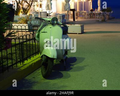 Vespa vert sauge classique garée près de la taverne au bord de l'eau à Kanoni, Corfou, Grèce Banque D'Images