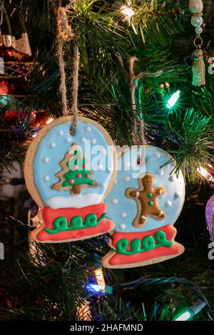 Deux décorations faites maison pour biscuits à la neige en forme de boule à sucre accrochées à un arbre de Noël. Banque D'Images