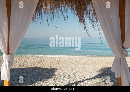 Lit de plage à baldaquin avec rideaux blancs sur la plage de sable Banque D'Images