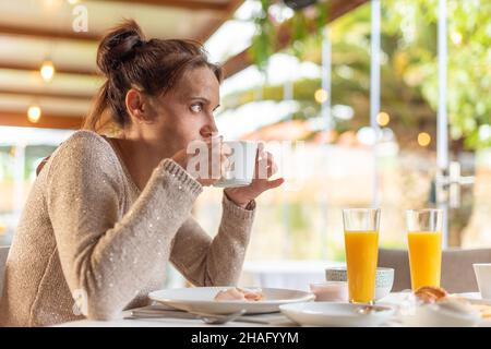 Femme prenant le petit déjeuner dans une salle à manger de l'hôtel. Banque D'Images