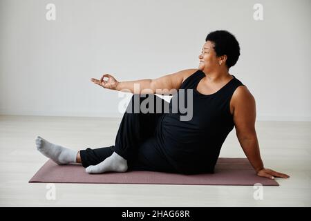 Portrait complet d'une femme âgée active qui apprécie le yoga à l'intérieur et souriant Banque D'Images