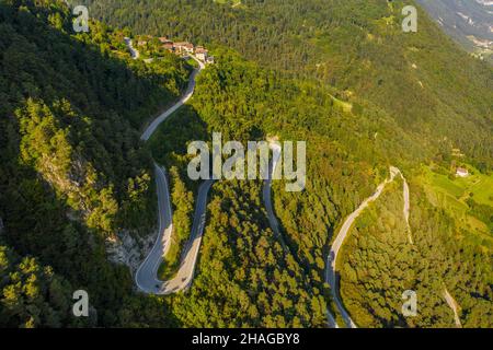 Vue aérienne de la route (SP53) qui s'enroule à travers la forêt au-dessus de la ville de Preore dans la région du Trentin en Italie Banque D'Images