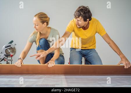 Couple marié installant un nouveau parquet stratifié en bois sur un plancher de film chaud.Système de chauffage au sol infrarouge sous sol stratifié Banque D'Images