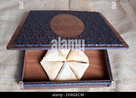 pestil, pulpe de fruit séchée, pestil turc hexagonal dans une ancienne boîte en bois sur le tissu de jute, en gros plan Banque D'Images