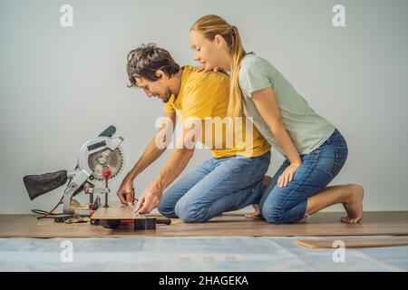 Couple marié installant un nouveau parquet stratifié en bois sur un plancher de film chaud.Système de chauffage au sol infrarouge sous sol stratifié Banque D'Images