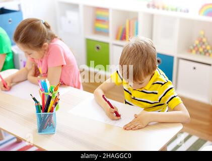 Les élèves de la salle de classe assis aux tables et écrivant une leçon. Banque D'Images