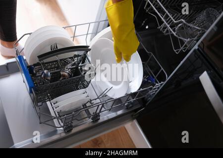 Une femme sort de la vaisselle propre du lave-vaisselle Banque D'Images