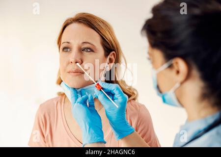 Service médical, maladies et virus covid.Une infirmière tenant un coton-tige et prenant un échantillon pour le test PCR du nez d'une femme. Banque D'Images