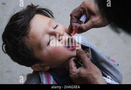 RAWALPINDI, Pakistan - décembre 13 : un agent de santé administre le vaccin contre la polio à un enfant lors d'une campagne anti-polio à Rawalpindi le 13 décembre 2021 Banque D'Images