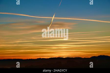 Le ciel de l'aube avec des pistes de vapeur d'avion croise en traversant montrant l'activité occupée de l'avion au-dessus du nord de l'Espagne Banque D'Images