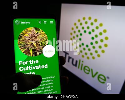 Personne tenant un smartphone avec le site Web de la société de marijuana médicale Trulieve Cannabis Corp. À l'écran avec le logo.Concentrez-vous sur le centre de l'écran du téléphone. Banque D'Images