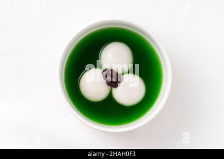 Vue de dessus du matcha grand tangyuan (tang yuan) avec soupe de matcha douce et pâte de haricots rouges dans un bol sur fond blanc pour la nourriture de festival. Banque D'Images