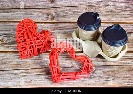 Sur un fond en bois, il y a deux tasses de café à droite, et à gauche deux grands coeurs tissés décoratifs de formes différentes pour le h Banque D'Images