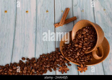 Il y a des grains de café dans une tasse inversée, et sont également striés sur le fond en bois au bas du cadre.Anis et cannelle près d'une tasse Banque D'Images