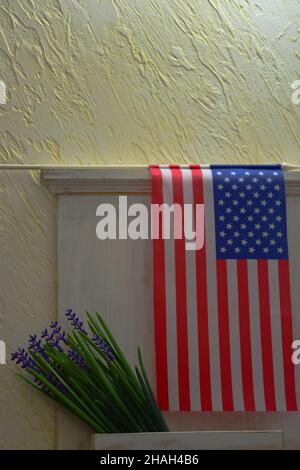 Drapeau américain dans une boîte aux lettres en bois avec un petit bouquet de fleurs accroché au mur Banque D'Images