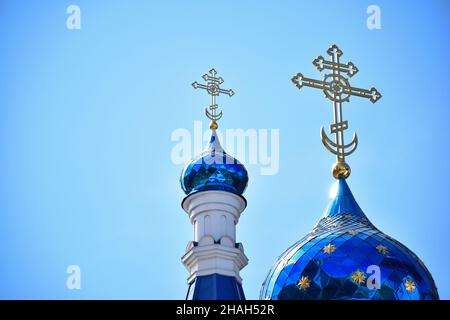 Sur fond de ciel bleu clair, deux dômes d'une église chrétienne ou d'un monastère de différentes tailles, avec des croix au sommet Banque D'Images