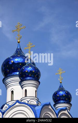 Sur fond de ciel clair, plusieurs dômes d'une église chrétienne de différentes tailles en bleu, avec des croix en haut. Banque D'Images