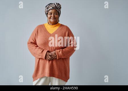 Portrait à la taille haute d'une femme âgée noire portant des imprimés ethniques et regardant l'appareil photo souriant sur fond blanc, espace de copie Banque D'Images