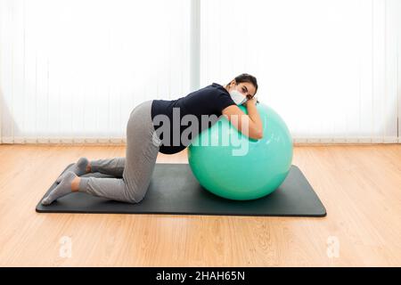 Une femme enceinte qui fait des exercices de respiration et se repose sur un ballon de fitness Banque D'Images