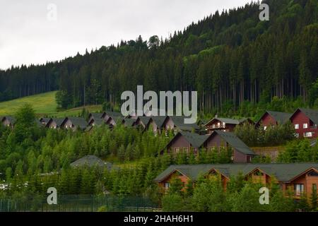 Sous la montagne d'été se trouvent des rangées de maisons d'hôtel au toit vert.Les pentes sont surcultivées avec des arbres Banque D'Images