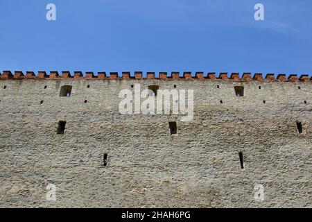 Mur médiéval en pierre d'un château ou d'une forteresse avec des sommets en briques dentelées.Il y a de petites échappatoires pour la prise de vue.Au-dessus du ciel bleu Banque D'Images