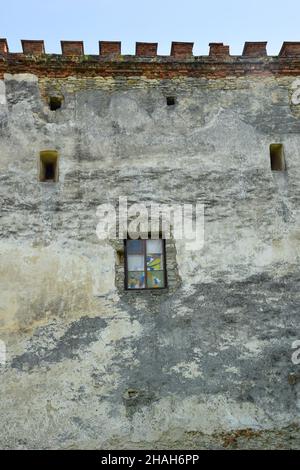 Mur médiéval en pierre d'un château ou d'une forteresse, au centre il y a une fenêtre avec mosaïque de verre.Il y a de petites échappatoires pour la prise de vue.Au-dessus de la bl Banque D'Images