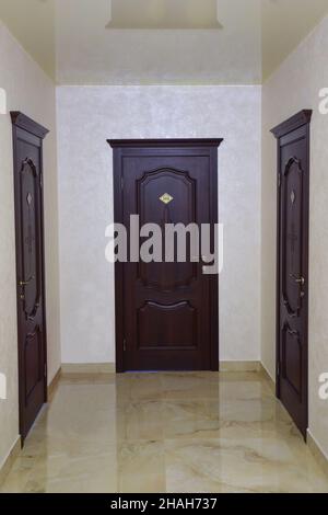 Un couloir dans un hôtel ou un immeuble de bureaux avec vue panoramique.Trois portes brunes fermées à l'extrémité et sur les côtés Banque D'Images