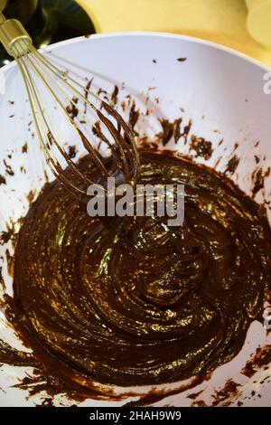 Faire du chocolat à la maison.Liquide et foncé sur un fond flou fouetté avec un fouet dans une plaque en plastique Banque D'Images