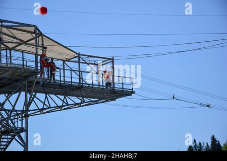 Sur la tour dans le parc d'attractions, un gars et une fille se prépare à sauter sur le saut à l'élastique.Photo de loin contre le ciel bleu Banque D'Images