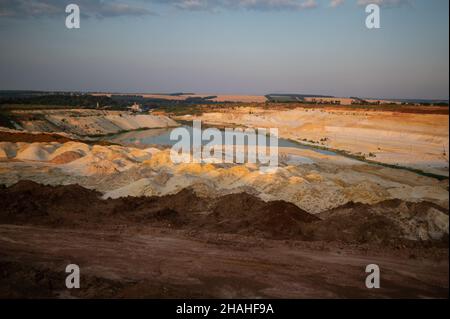 Carrière de sable. Lagon turquoise et mine de surface avec des minéraux colorés exposés, équipement au fond de la fosse. Banque D'Images