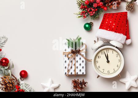 Composition de Noël en hiver.Réveil chapeau de père Noël cadeau branches de sapin sur un fond blanc.Vue de dessus de la pose à plat Banque D'Images