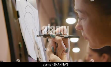 Une artiste apprend à peindre avec un aérographe avec du colorant acrylique, du papier et du chevalet.Concept art moderne, aérographe, aérographie, graffiti, aérosol Banque D'Images