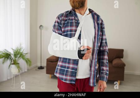 Un homme qui a cassé le bras, la main, le poignet ou le coude porte un bandage et une élingue de soutien Banque D'Images