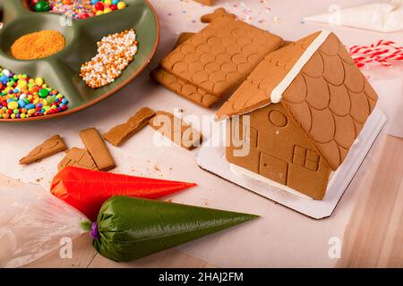 Les enfants assemblent et décorent une maison de pain d'épice à l'heure de Noël.Tradition familiale de Noël, artisanat de Noël. Banque D'Images
