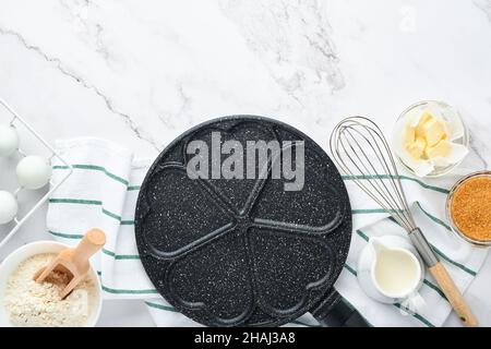 Poêle à frire vide noire, poêle avec revêtement antiadhésif en pierre pour cuire des crêpes en forme de coeur de petit déjeuner et des ingrédients sur la table en béton gris Banque D'Images